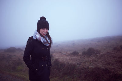 Portrait of young woman standing on land against sky