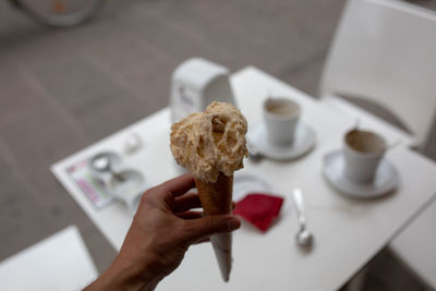High angle view of hand holding ice cream on table