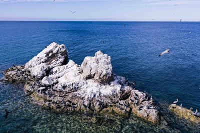 High angle view of rock formation in sea against sky