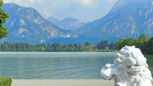 Statue by lake against mountains