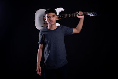 Full length of young man standing against black background
