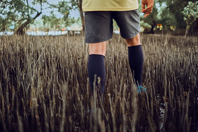 Low section of man standing on mangrove forest