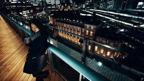 High angle view of woman standing on illuminated bridge