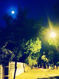 Illuminated street light against sky at night