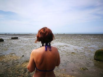 Rear view of woman standing at beach