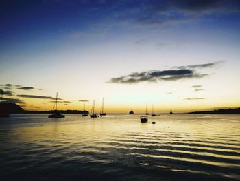 Silhouette sailboats in sea against sky during sunset