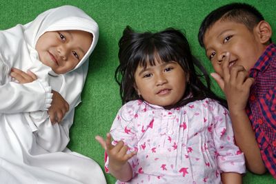 High angle portrait of siblings lying on carpet at home