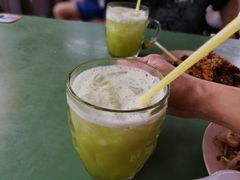 Close-up of hand holding drink on table