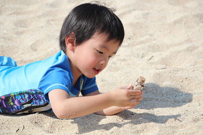 Boy holding toy on sand at beach shore