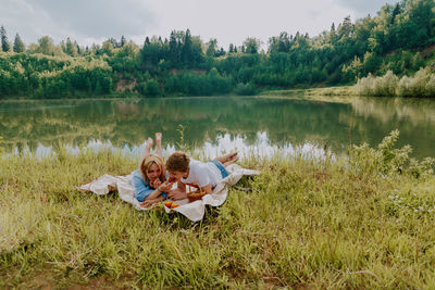 People sitting on grass by lake