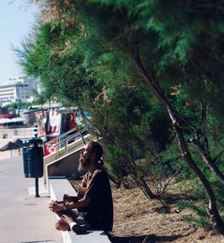 Side view of couple sitting on tree