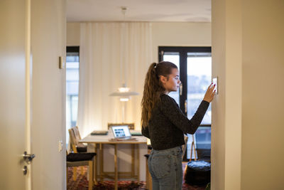 Side view of woman using mobile phone at home