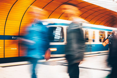 Blurred motion of people against train at subway station