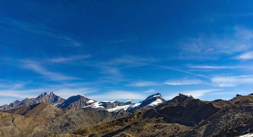 Scenic view of snowcapped mountains against blue sky