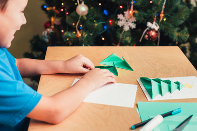 Midsection of child on table at illuminated christmas tree