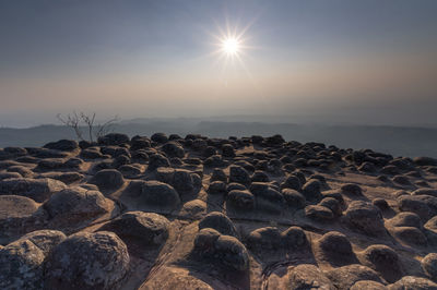 Rocks on beach against sky during sunset