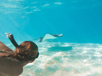 Rear view of woman swimming by stingray in sea