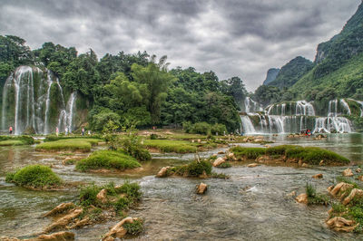 Scenic view of waterfall in forest against sky