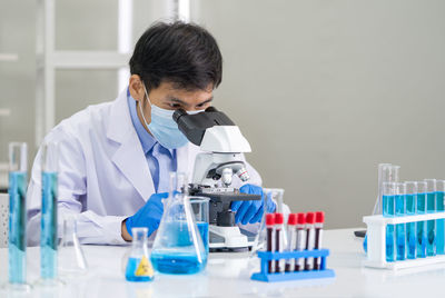 Scientist wearing surgical mask experimenting at laboratory