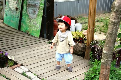 Full length of cute smiling girl looking away while standing on floorboard