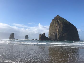 Rock formations on beach against sky