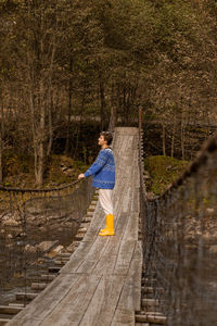 Side view of man standing on wood in forest