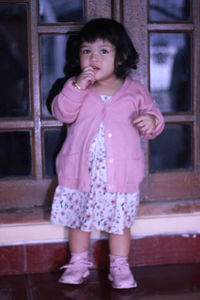 Portrait of cute girl standing against wall