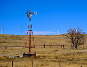 Windmill on field against clear blue sky