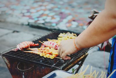 Cropped image of woman preparing food on barbecue grill