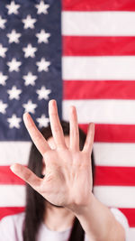 Young woman stretch out her palm to camera anti domestic violence american flag on background. 