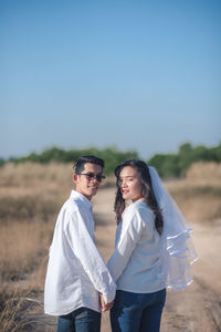 Young couple standing on land against sky