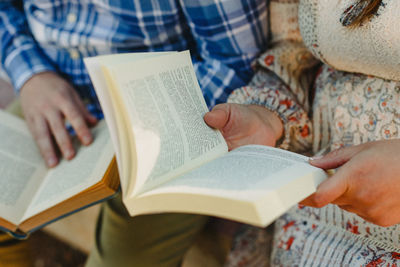 Midsection of people reading books while sitting