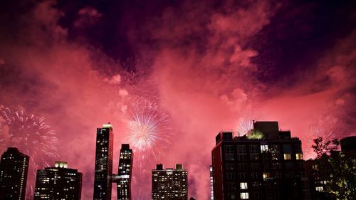 Low angle view of firework display over buildings at night