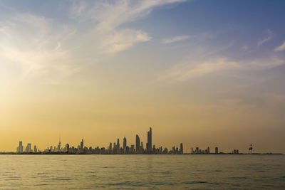 Panoramic view of sea and buildings against sky during sunset