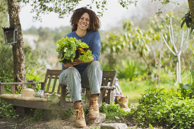 Portrait of smiling young woman holding plants