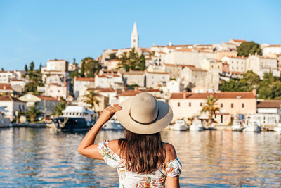 Young woman in white dress in front of old town by sea, summer, travel, vacation, lifestyle.