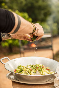 Cropped hands of man squeezing limes on food in container