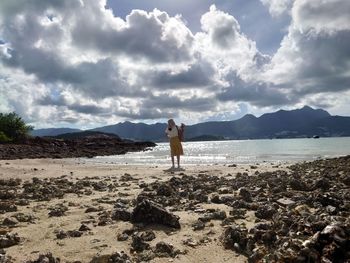 Woman standing on beach against sky