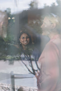 Portrait of smiling young woman standing against trees