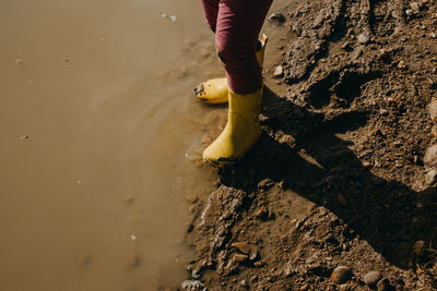 Yellow rubber boots on puddle
