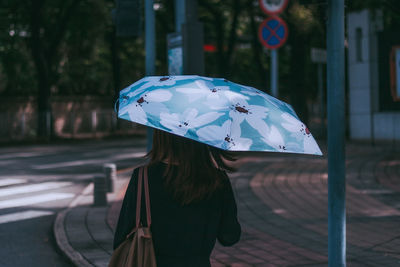 Woman holding umbrella standing on street