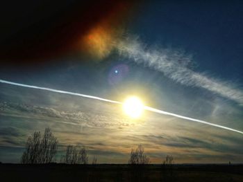 Low angle view of vapor trails in sky at sunset