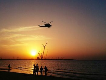 Silhouette of people in sea at sunset