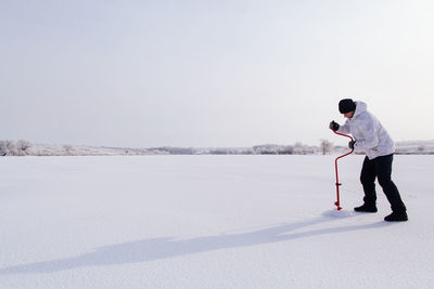 Full length of man standing with pole on snow against sky