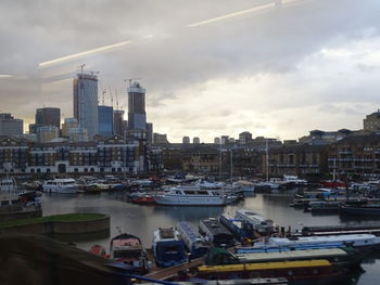 Sailboats moored on river by buildings in city against sky