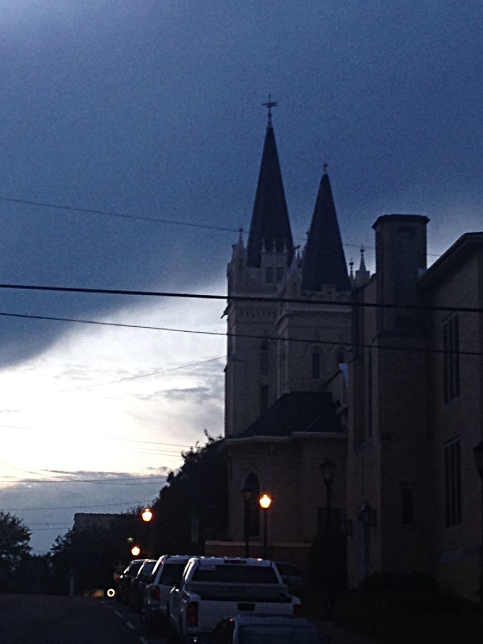 building exterior, architecture, built structure, church, religion, transportation, sky, place of worship, car, road, land vehicle, street, spirituality, mode of transport, cloud - sky, dusk, silhouette, outdoors