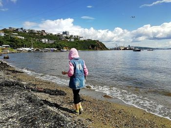 Rear view of woman on beach against sky