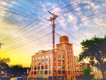 Low angle view of electricity pylon against cloudy sky