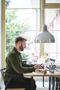 Smiling entrepreneur using laptop while sitting and working at home