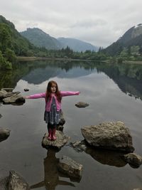 Girl standing on rock against lake